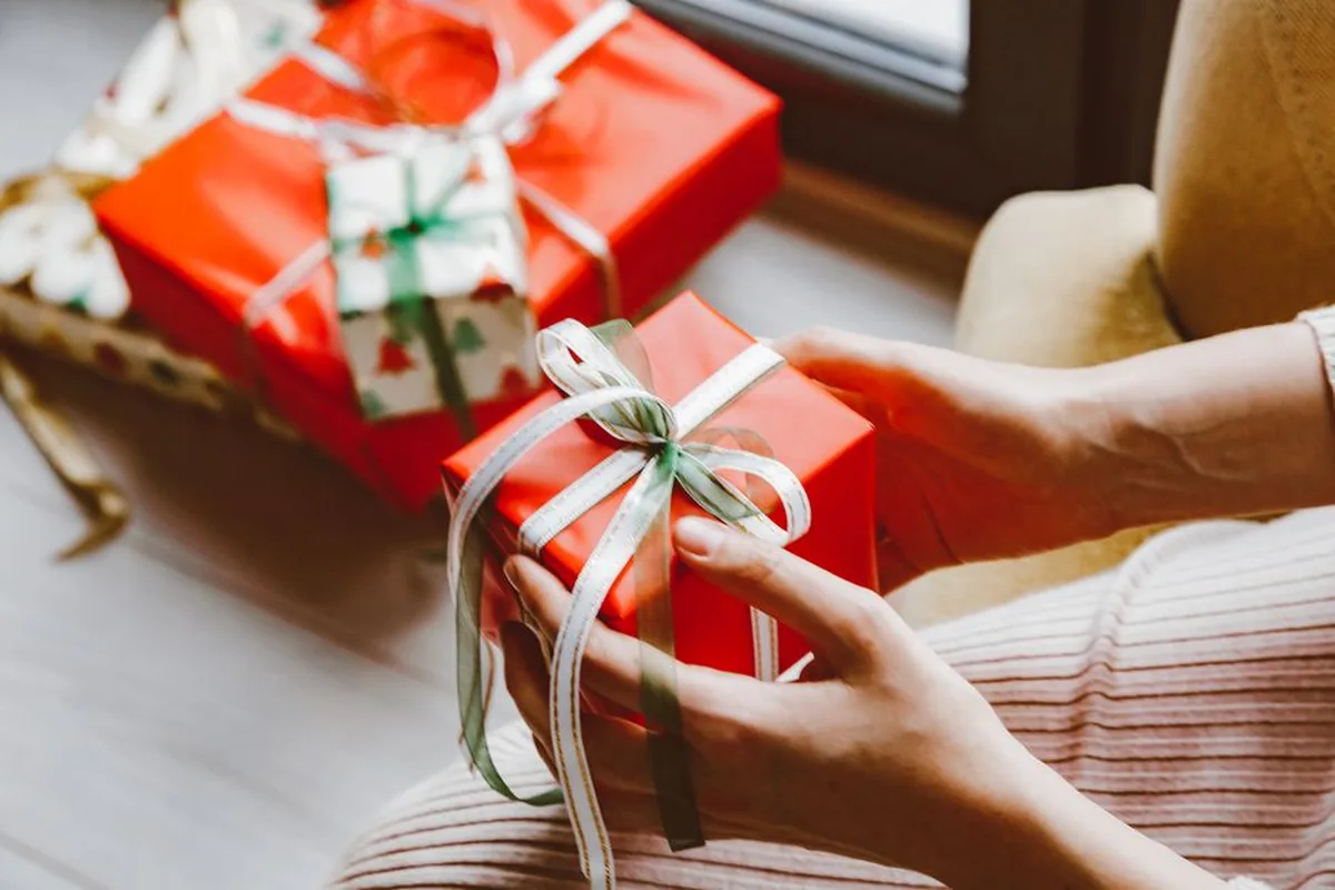 Hands wrapping a red gift box for a friend